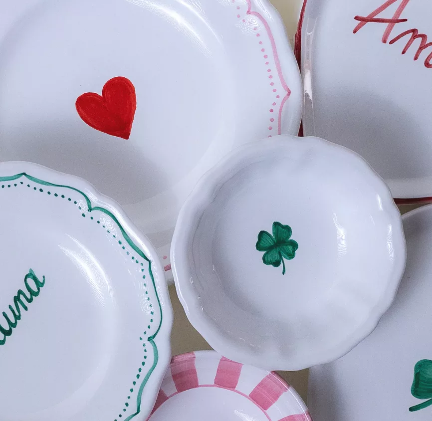 Assiettes italiennes artisanales peintes à la main, décorées de motifs symboliques comme un cœur et un trèfle, illustrant l’art de la table et la gastronomie méditerranéenne.