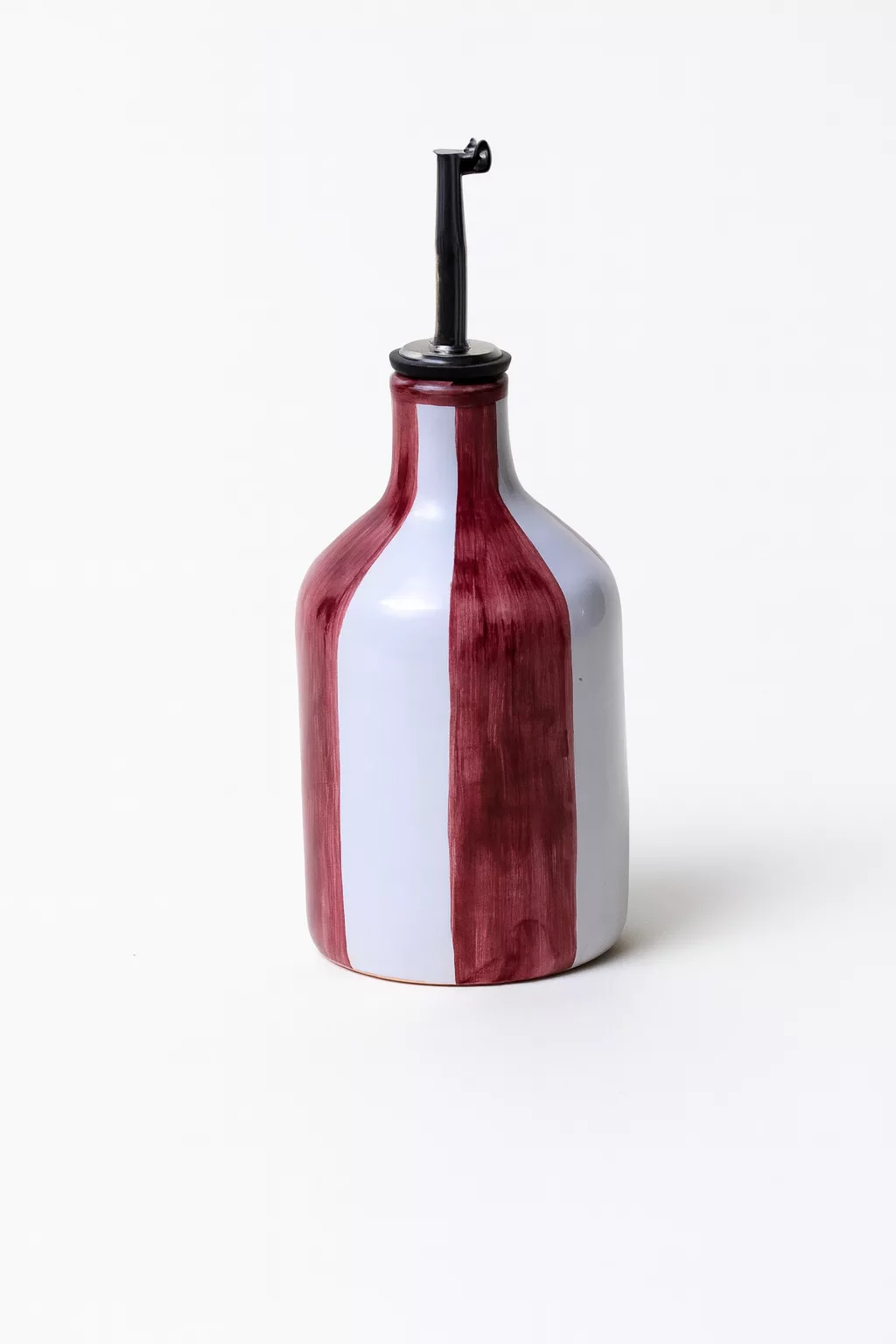 Huilier en céramique peint à la main avec des rayures rouges et blanches, bouchon verseur en métal, dans un style artisanal méditerranéen.